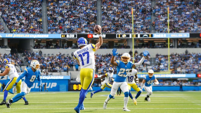 Los Angeles Rams QB Baker Mayfield throws the ball while being pressured by Los Angeles Chargers CB Bryce Callahan at SoFi Stadium in Inglewood, California.