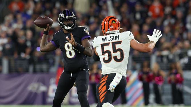 Lamar Jackson looks to pass while being pressured by Cincinnati Bengals LB Logan Wilson at M&T Bank Stadium in Baltimore, Maryland.