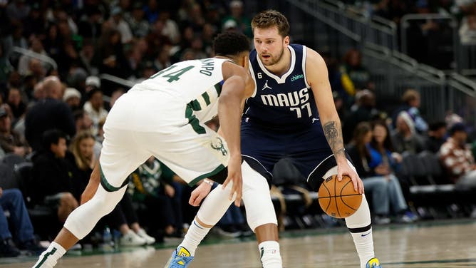 Dallas Mavericks All-Star Luka Doncic cradles the rock vs. Bucks' PF Giannis Antetokounmpo at Fiserv Forum in Milwaukee, Wisconsin.