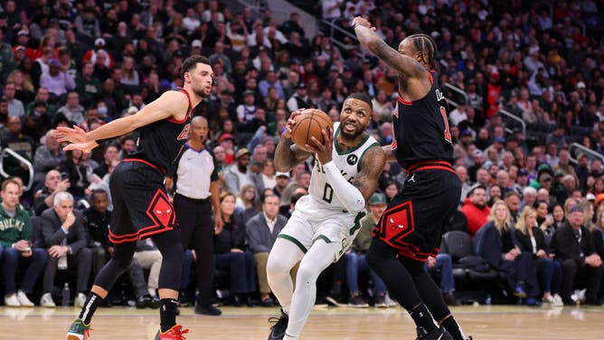 Bucks PG Damian Lillard drives past Chicago Bulls wings DeMar DeRozan and Zach LaVine at Fiserv Forum in Milwaukee, Wisconsin.