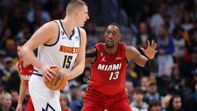 Heat big Bam Adebayo defends Nuggets big Nikola Jokic at Ball Arena.