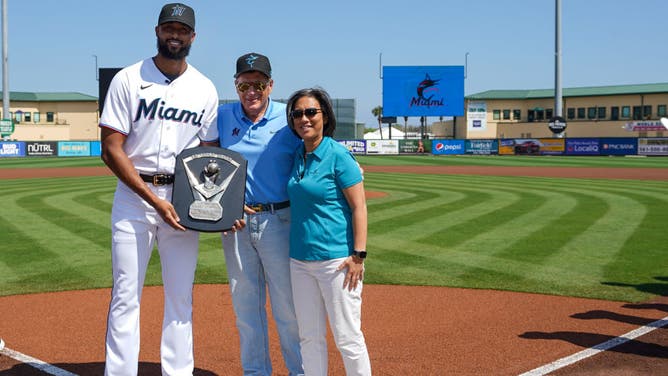 Sandy Alcantara receives his 2022 NL Cy Young award from team owner Bruce Sherman and general manager Kim Ng at Roger Dean Stadiu. in Jupiter, Florida.