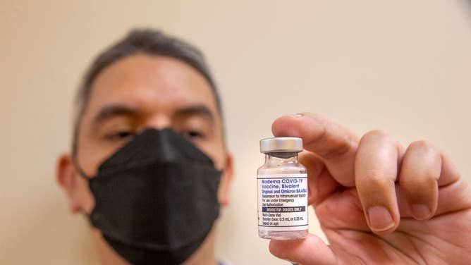 Doctor holds up COVID booster shot.