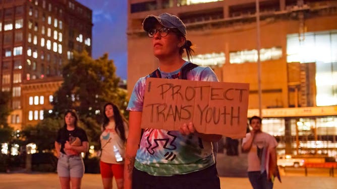 A woman stands in front of the Ohio Statehouse to protest against legislation banning transgender women from participating in female sports. 