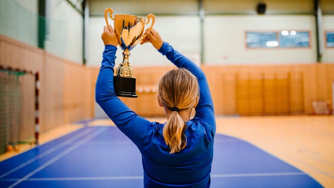 A young girl holding up a trophy.