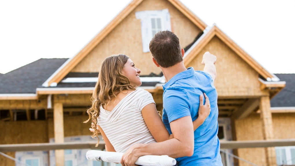 Caucasian couple admiring house under construction