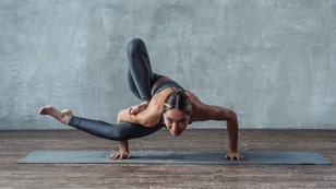 athletic strong woman doing yoga exercise pose standing on hands.