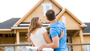 Caucasian couple admiring house under construction