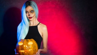 Beautiful girl with a painted face posing with Jack O' Lantern