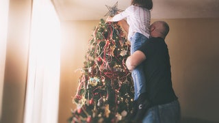 343b448c-dad lifting daughter to put Star tree topper on Christmas tree