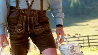 Farmer carrying milk cans, midsection