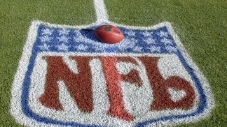 A Football Sits On A Field With The NFL Shield Painted On It