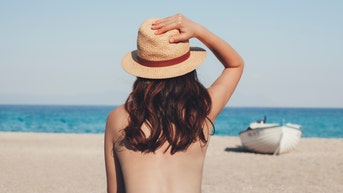 Greece, young woman on the beach looking at the sea