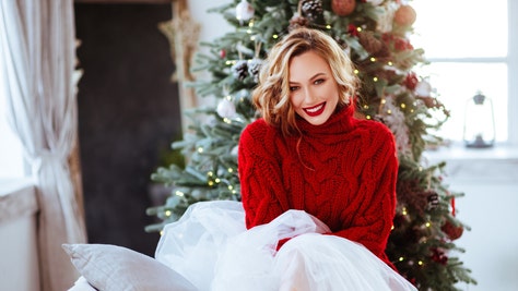 6280947c-smiling woman in red sweater over christmas tree background