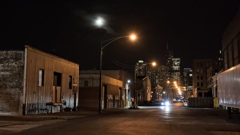 Urban city street with vintage industrial warehouses and the Chicago skyline with the moon at night