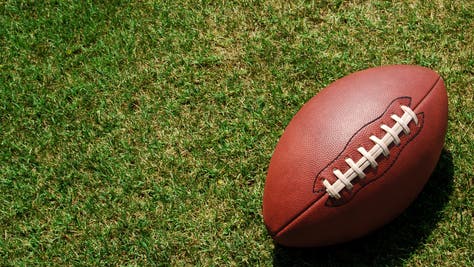 A lone football resting in the green grass