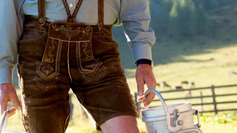 Farmer carrying milk cans, midsection