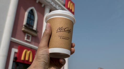 Someone produly hoisting a cup of McDonald's coffee