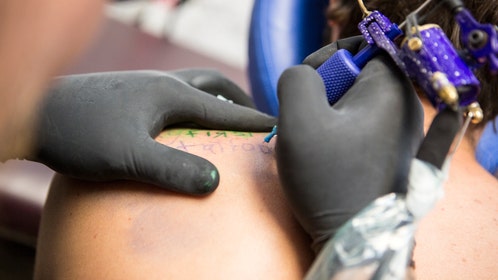 Close up of tattooist giving customer their first tattoo