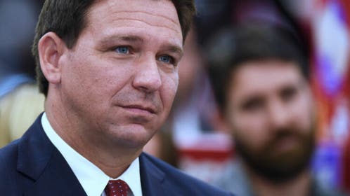 Florida Governor Ron DeSantis listens to a speaker at a