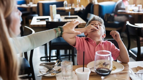 Mother stopping son eating noodles in restaurant
