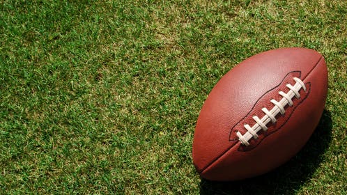 A lone football resting in the green grass
