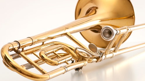 Old and used trombone on white background.