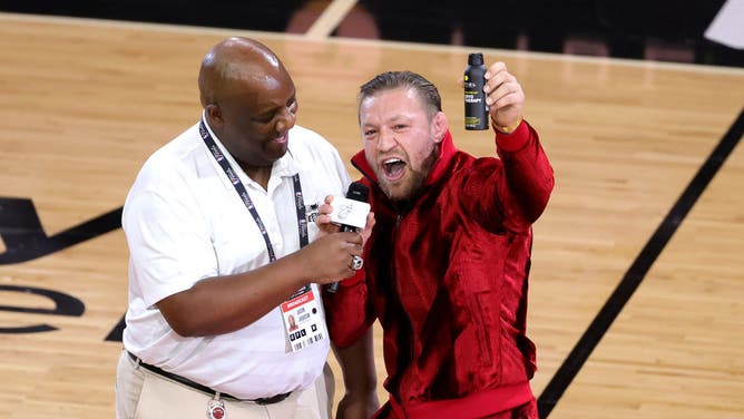 Connor McGregor promotes some type of pain relief spray during the Miami Heat game