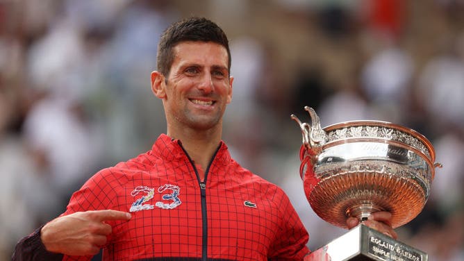 Novak Djokovic of Serbia celebrates with the winners trophy as he points to the number 23 on his jacket after victory against Casper Ruud of Norway in the Men's Singles Final match of the 2023 French Open.
