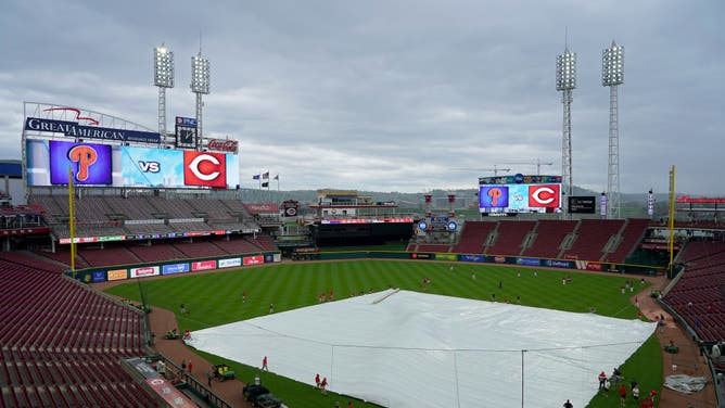 The grounds crew pulls a tarp across the field during a rain delay before the game between the Philadelphia Phillies and the Cincinnati Reds at Great American Ball Park on April 16, 2023 in Cincinnati, Ohio.