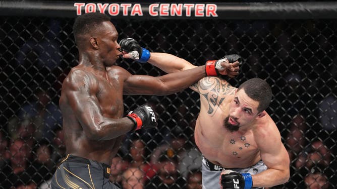 Robert Whittaker punches Israel Adesanya in their UFC Middleweight championship fight during the UFC 271 event at Toyota Center in Houston, Texas.