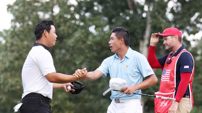 South Korean Tom Kim and American Collin Morikawa shake hands on the 17th green during the Thursday foursome matches in the 2022 Presidents Cup at Quail Hollow Country Club in Charlotte, North Carolina.