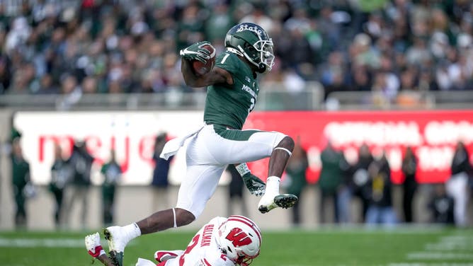 Michigan State player hurdles a Wisconsin defender in Big Ten action.