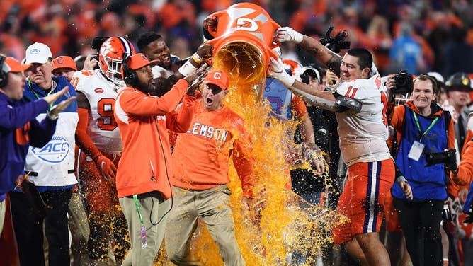 Myles Murphy #98 and Bryan Bresee #11 of the Clemson Tigers dump Gatorade on head coach Dabo Swinney as the clock expires during the ACC Championship game.