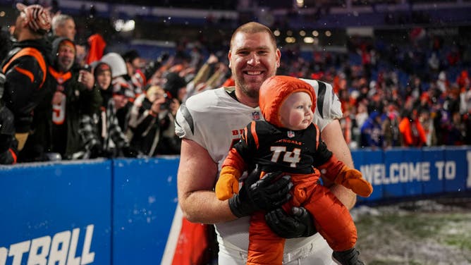 Max Scharping of the Cincinnati Bengals celebrates with his child following a Wild Card win over the Bills.