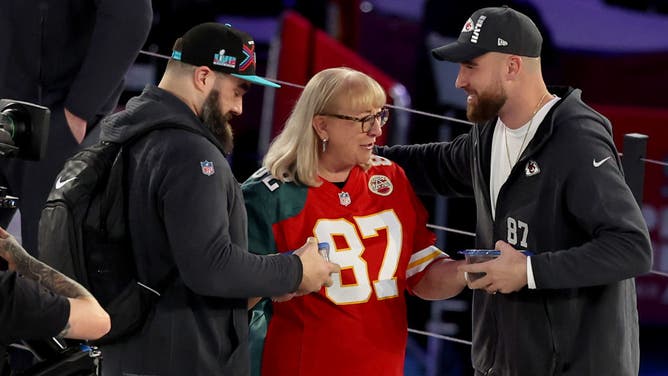 Mother Donna Kelce gives cookies to her son's Jason Kelce of the Philadelphia Eagles and Travis Kelce of the Kansas City Chiefs during Super Bowl LVII Opening Night.