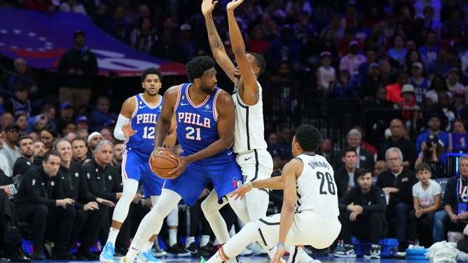 76ers big Joel Embiid controls the ball while Nets big Nic Claxton and PG Spencer Dinwiddie crowd him at the Wells Fargo Center.