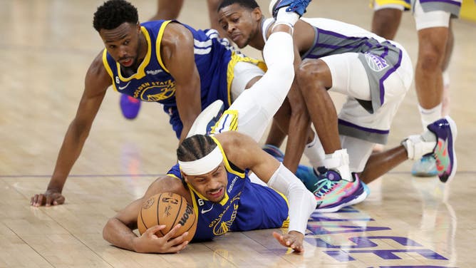 Warriors SG Moses Moody dives over teammate Andrew Wiggins and Kings PG De'Aaron Fox to get a loose ball in Game 6 of the Western Conference 1st-Round Playoffs at Chase Center in San Francisco.