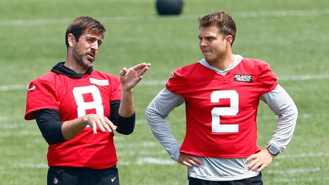 Quarterbacks Aaron Rodgers and Zach Wilson of the New York Jets talk during practice.