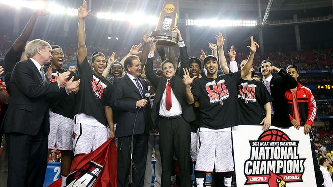 Louisville head coach Rick Pitino holds up the 2013 Men's college basketball national title trophy.
