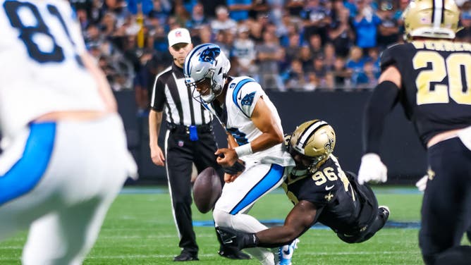 Bryce Young of the Carolina Panthers fumbles the ball as he takes a hit by Carl Granderson of the New Orleans Saints.