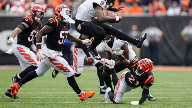 Baltimore Ravens QB Lamar Jackson leaps over Bengals CB Mike Hilton while running with the ball at Paycor Stadium in Cincinnati, Ohio.