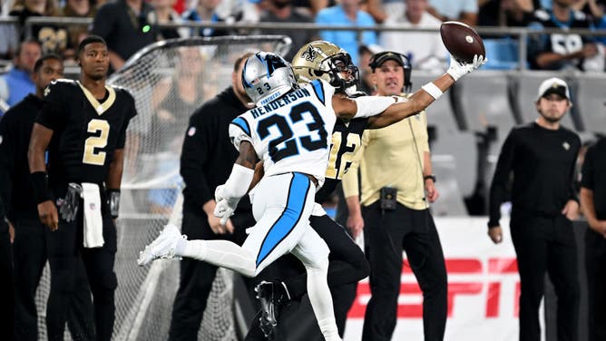 Chris Olave of the New Orleans Saints bobbles and catches a 42-yard pass against CJ Henderson of the Carolina Panthers during the third quarter in the game at Bank of America Stadium on September 18, 2023 in Charlotte, North Carolina.