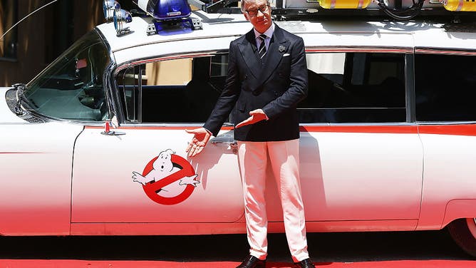 Paul Feig poses in front of a Ghostbusters vehicle, a massive 2016 Hollywood flop thanks to its forced woke messaging.
