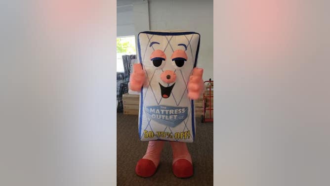Drunk Woman Pushed Over Mattress Outlet Mascot
