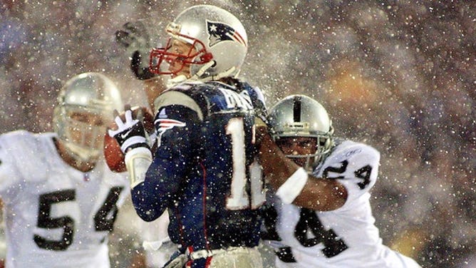 New England Patriots quarterback Tom Brady takes a hit from Charles Woodson of the Oakland Raiders on a pass attempt in the last two minutes of the game in their AFC playoff January 19, 2002 in Foxboro, Massachusetts.