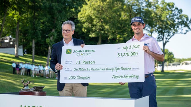 J.T. Poston holds his giant check with John Deere agriculture and turf President Mark Von Pentz after winning the 20223 John Deere Classic.