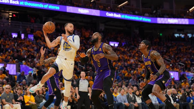 Golden State Warriors legend Stephen Curry passes the ball in front of LA Lakers' LeBron James in Game 2 of the 2023 NBA playoffs at the Chase Center.