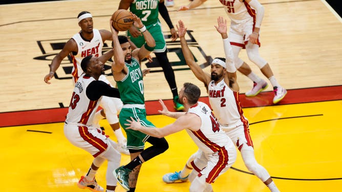 Celtics wing Jayson Tatum throws a jump-pass while being crowded by Heat C Bam Adebayo, PF Kevin Love, and Vincent at Kaseya Center.