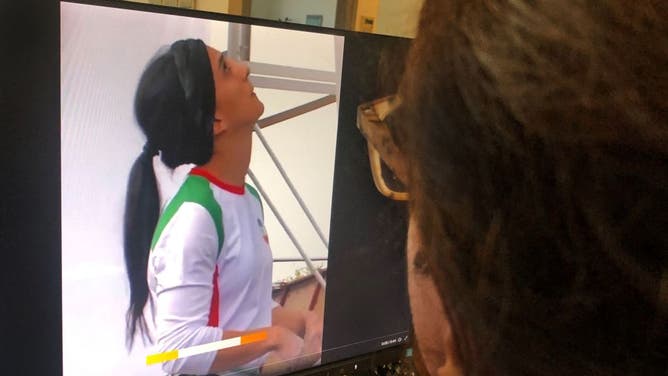 A woman looks at a screen displaying a video of an international climbing competition in Seoul, South Korea, during which Iranian climber Elnaz Rekabi competes without a hijab which is forbidden for Iranian female athletes.
